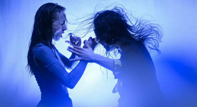 Zwei Frauen mit wehenden Haaren im blauen Licht, eine schreit.